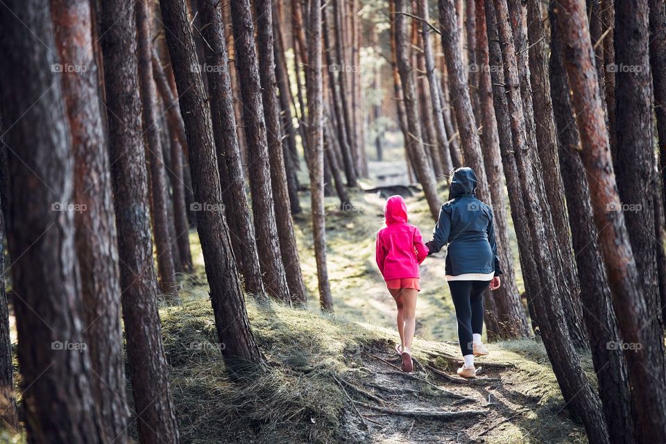 Summer vacation trip close to nature. Family walking in forest. People actively spending leisure time. Back view of woman with daughter enjoying long walk during summertime. Travel concept