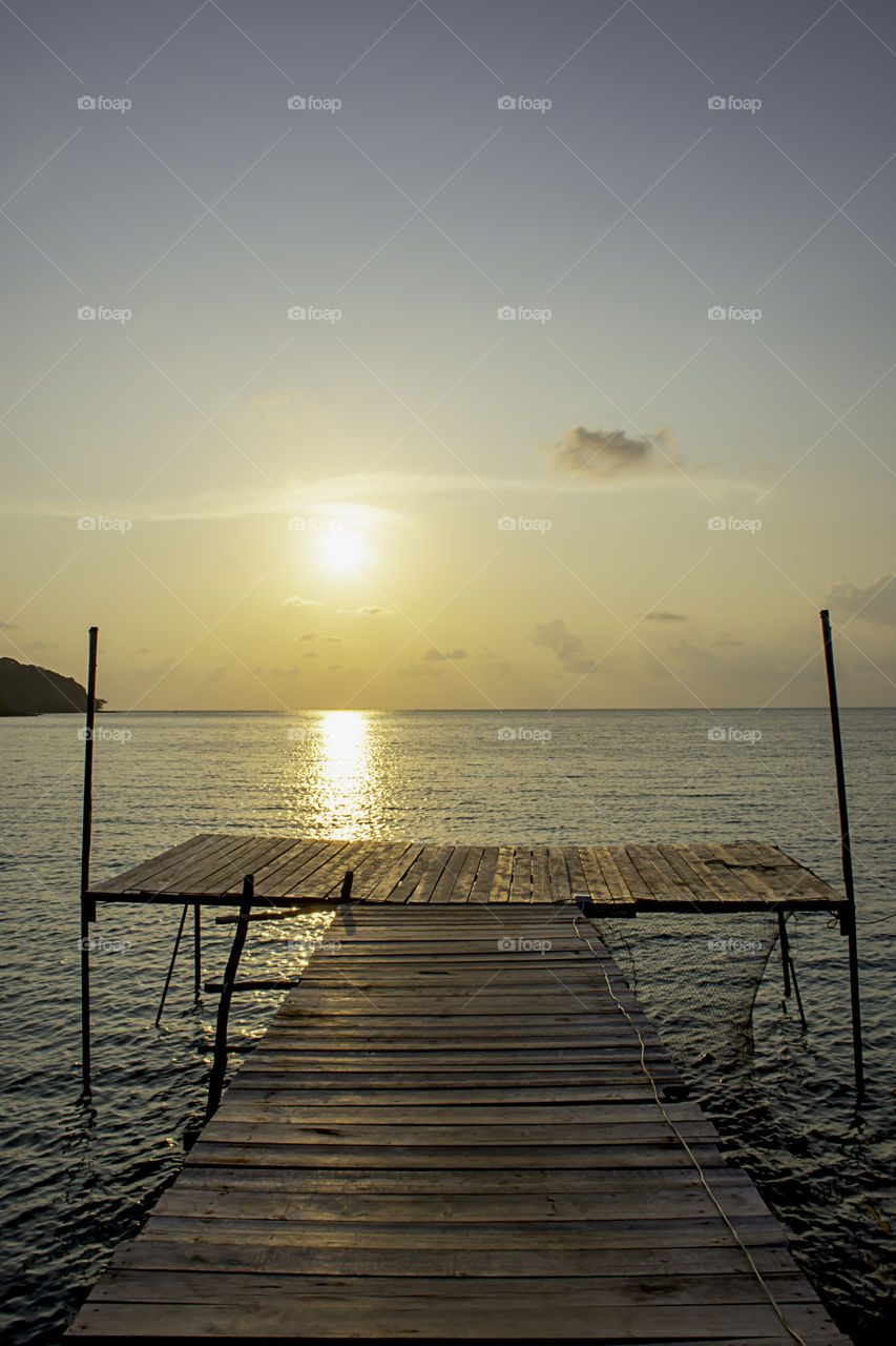 Wooden bridge in the sea and Golden reflections of the Sun