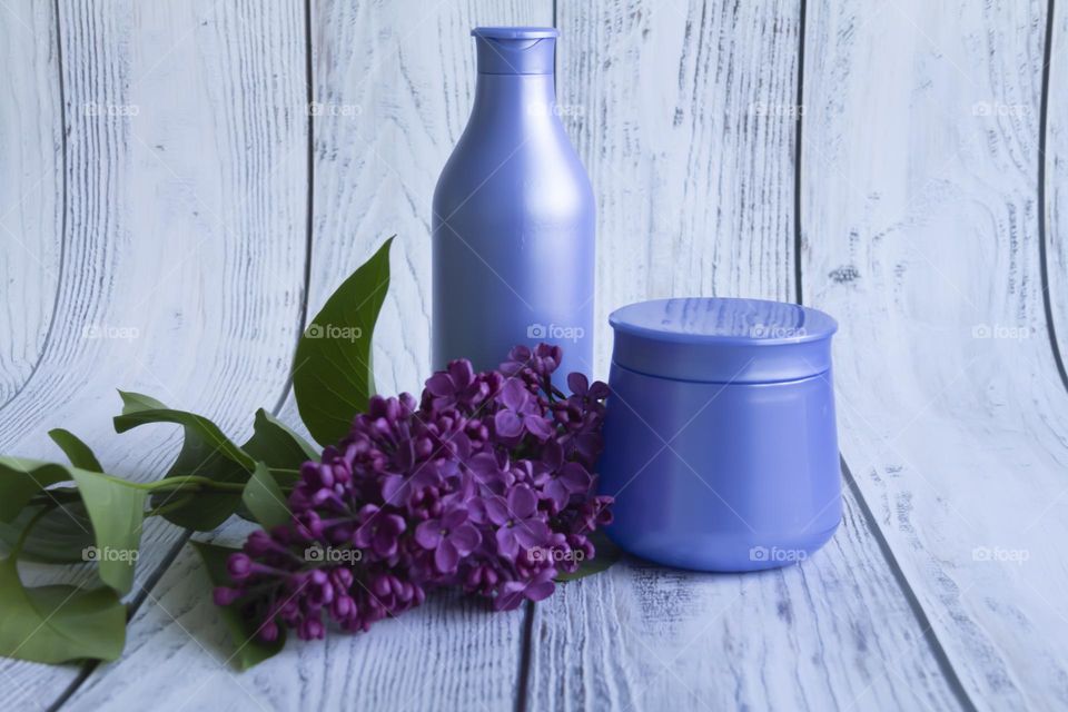 Jars with cosmetic products, beauty cosmetics in purple jars with fragrant flowers.