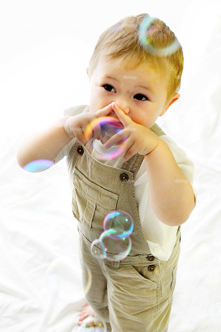 Upright studio picture of white boy, aged two with hands raised as