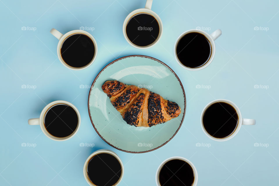 Business working morning with cup of hot coffee, fresh delicious croissant on blue background close up. Top view, copy space, flat lay, mockup.