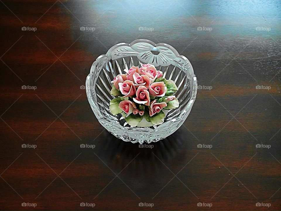 Ceramic pink flower in a glass bowl on a wood table