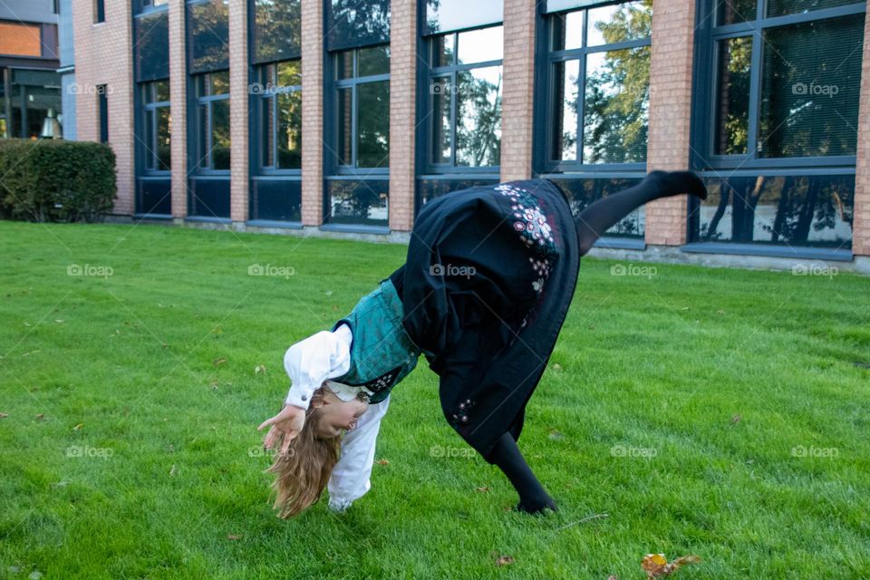 another little girl dancing and having fun in the garden ,while she using her norwegian dress