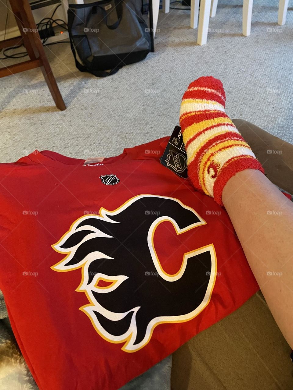 Funky, colourful yellow, white, red, soft Calgary Flames sock on my foot, to wear with the colourful, red, black, yellow, and white Calgary Flames jersey, when I go watch a hockey game, which I got as gifts for Christmas