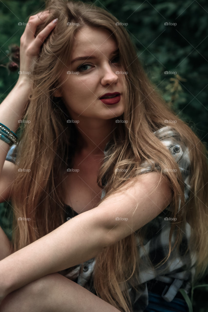 A girl with blond hair in a plaid shirt and short denim shorts on a background of trees and nature Girl, woman, man, people, blonde, blonde hair, checkered shirt, shorts shorts, denim shorts, forest nature, trees, grass, feelings, emotions tenderness, love, lifestyle, lifestyle, recreation