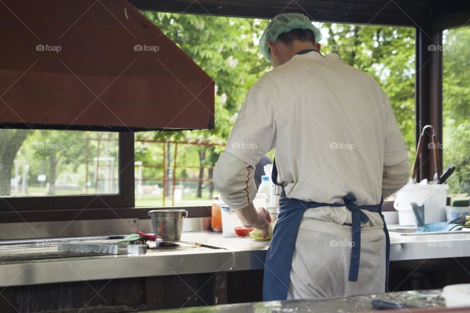 The back view of chef preparing food in a kitchen of outdoor restaurant