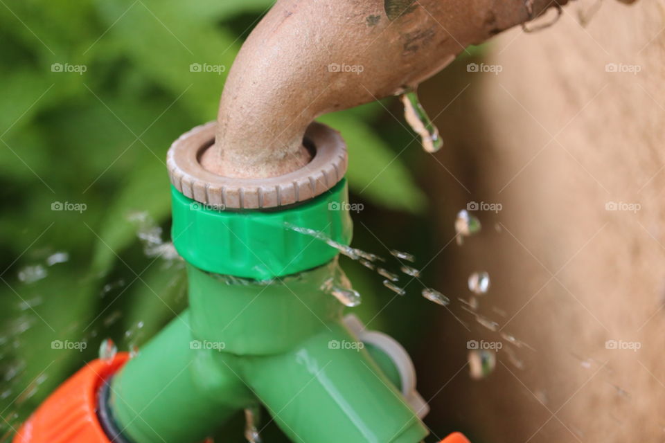 Water faucet with attached house spraying leaking water 