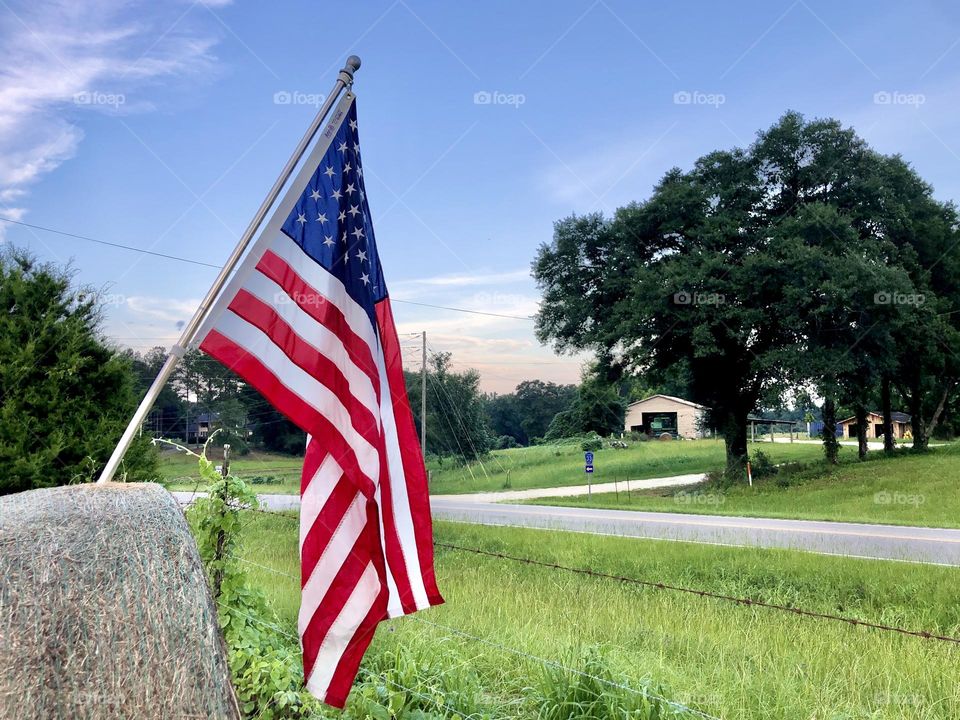 Summer holiday in United States. US flag mounted on hay bale in rural setting.