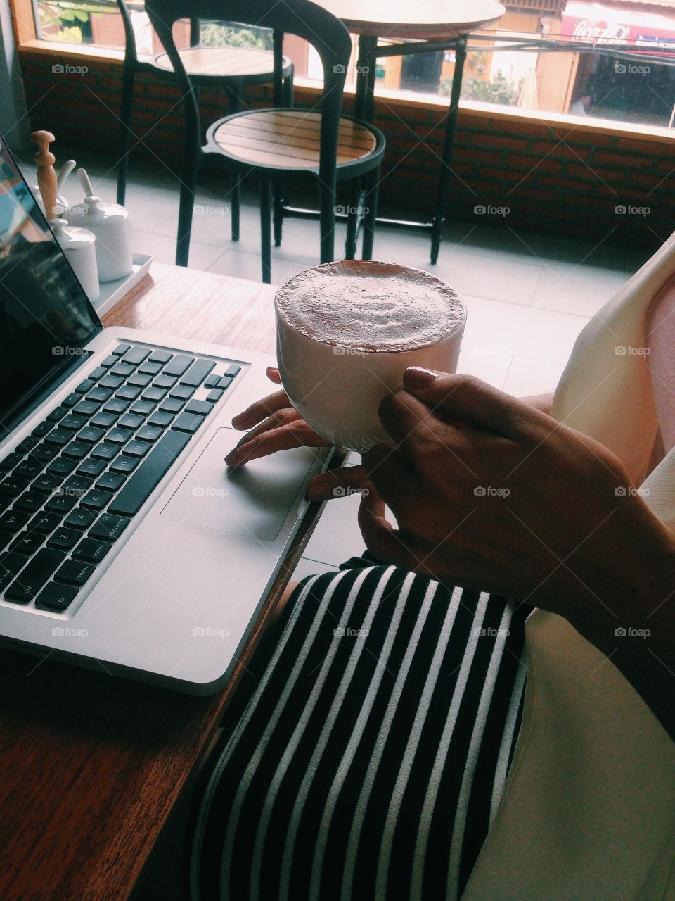 Woman working on laptop while drinking coffee