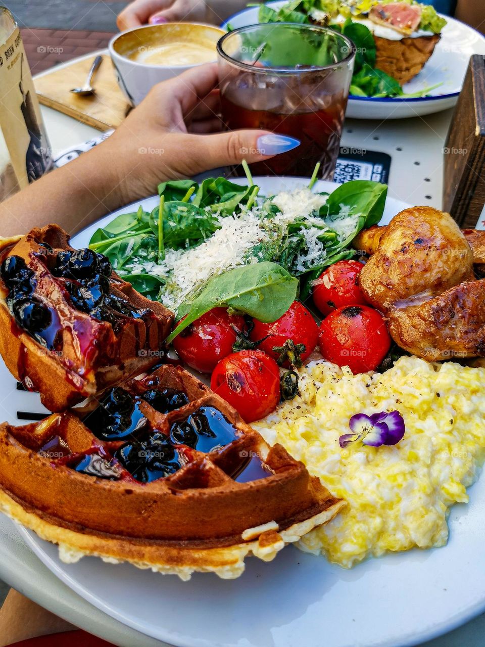 Unbelievably delicious lunch with crispy waffles, scrambled egg, grilled tomatoes and salad