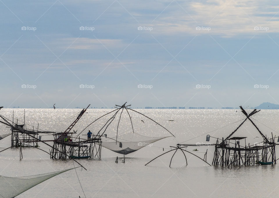 Silhouette of mother and son work on big fish trap together in the Southern of Thailand