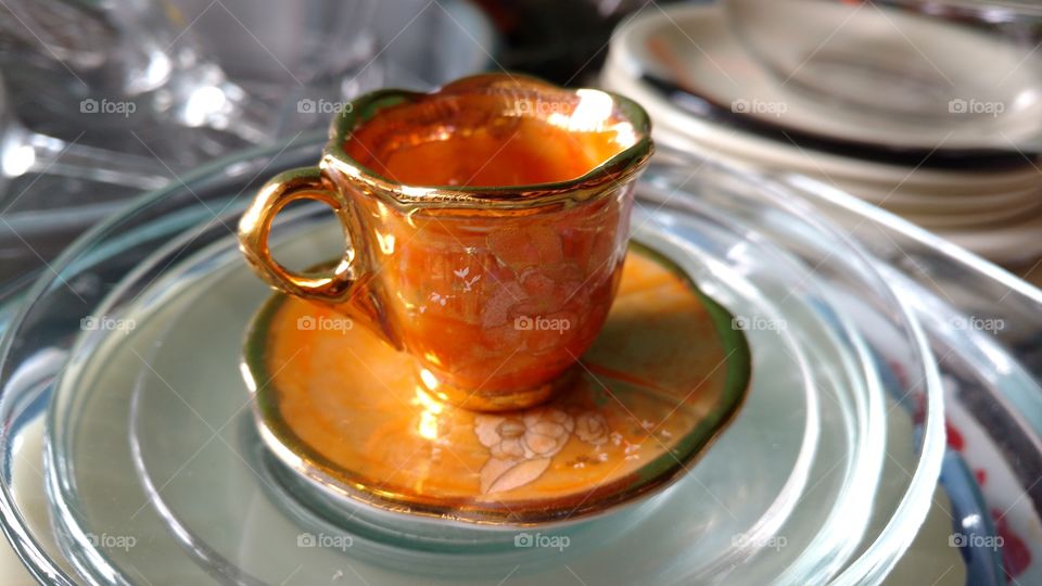 Gold colored cup on saucer