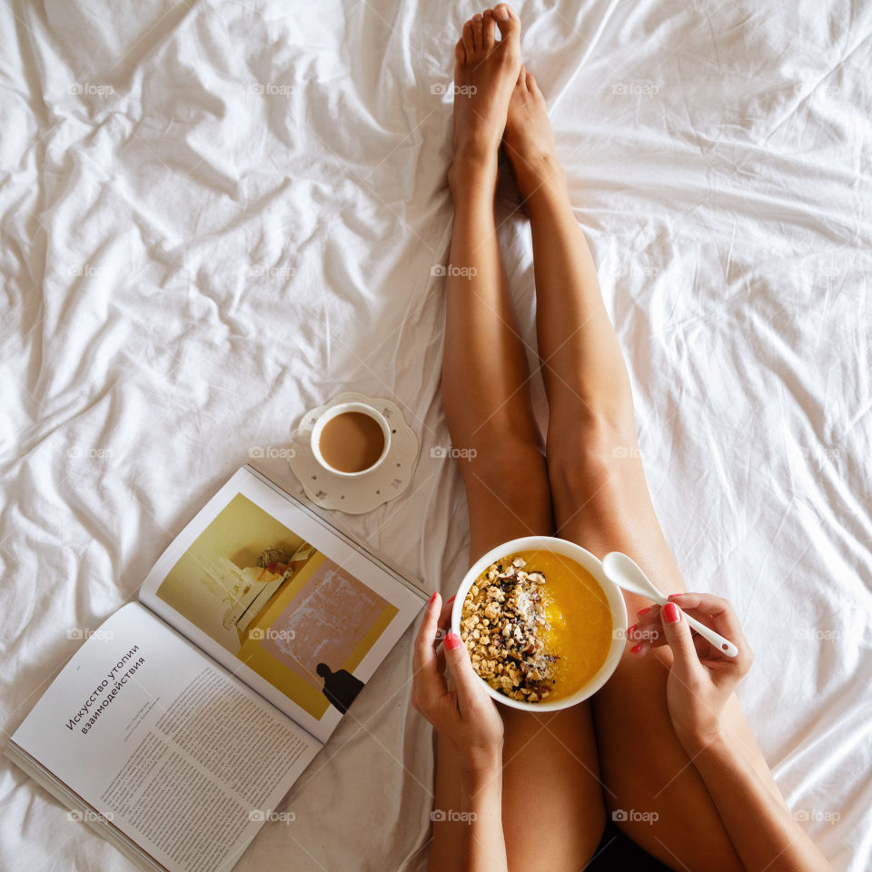 Woman eating breakfast on the bed