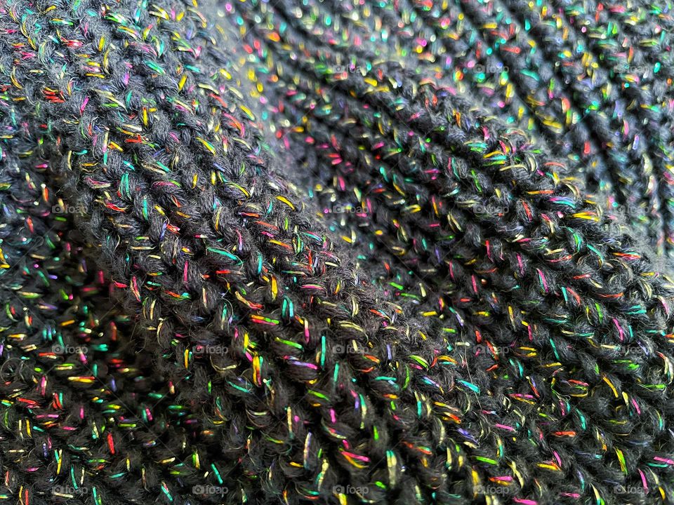 Knitted wool with metallic rainbow thread. Close up textured image suitable for a background