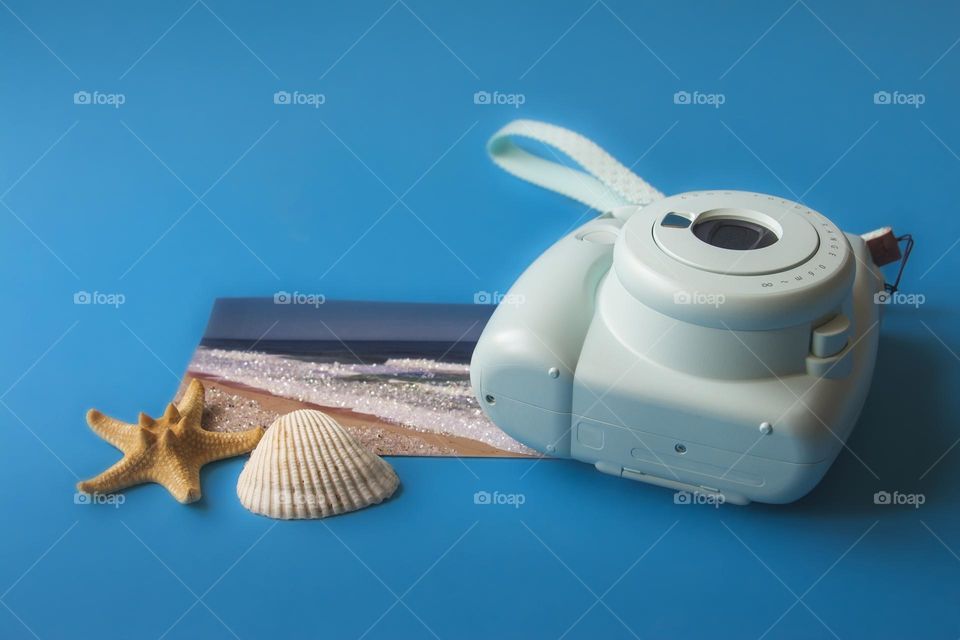 Camera and seashells on blue background