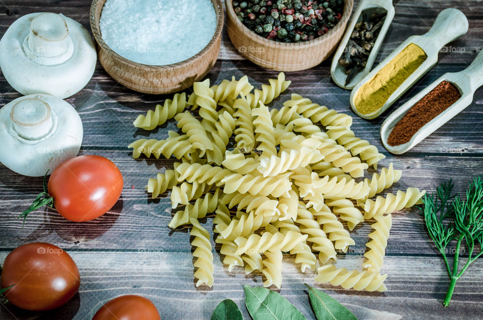 Raw pasta with ingredients and wooden accessories