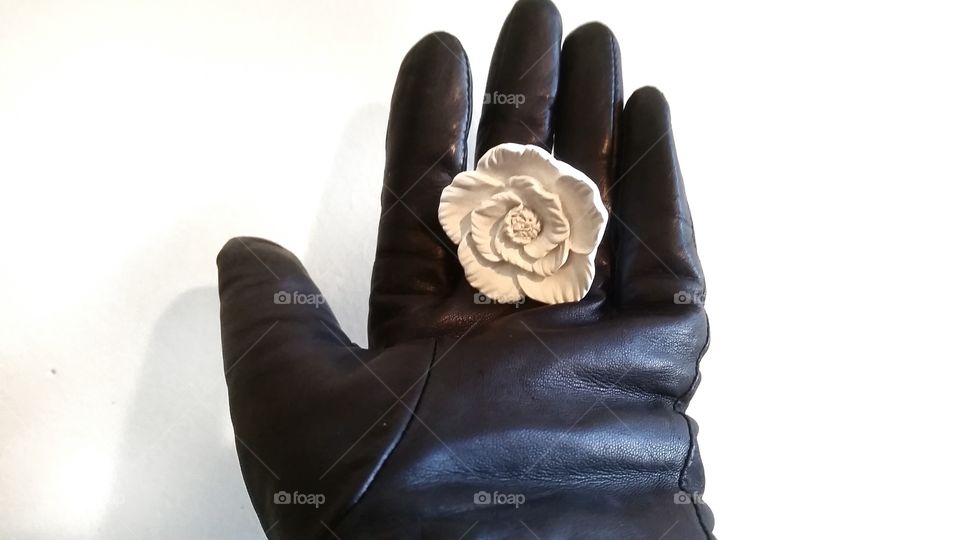 Black glove holding a fake rose.