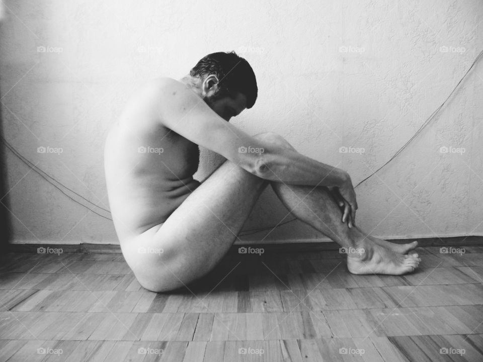 naked man sitting on the floor in the room