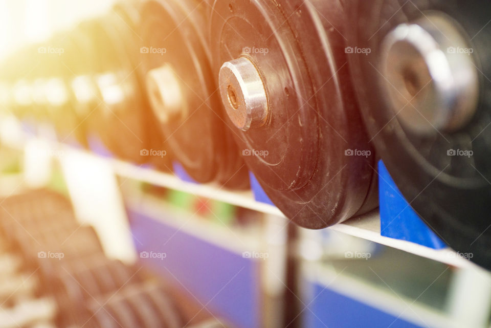 Image of black dumbbells in rows in a modern firtness center. Rows of dumbbells in the gym