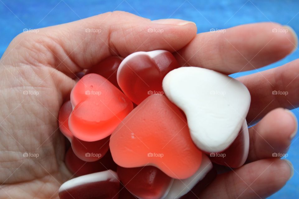 hearts valentine's jelly beans in hand blue background