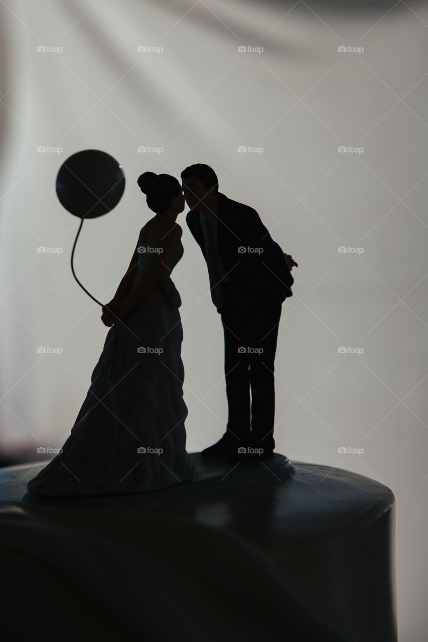 Silhouette of a couple on the cake topper kissing