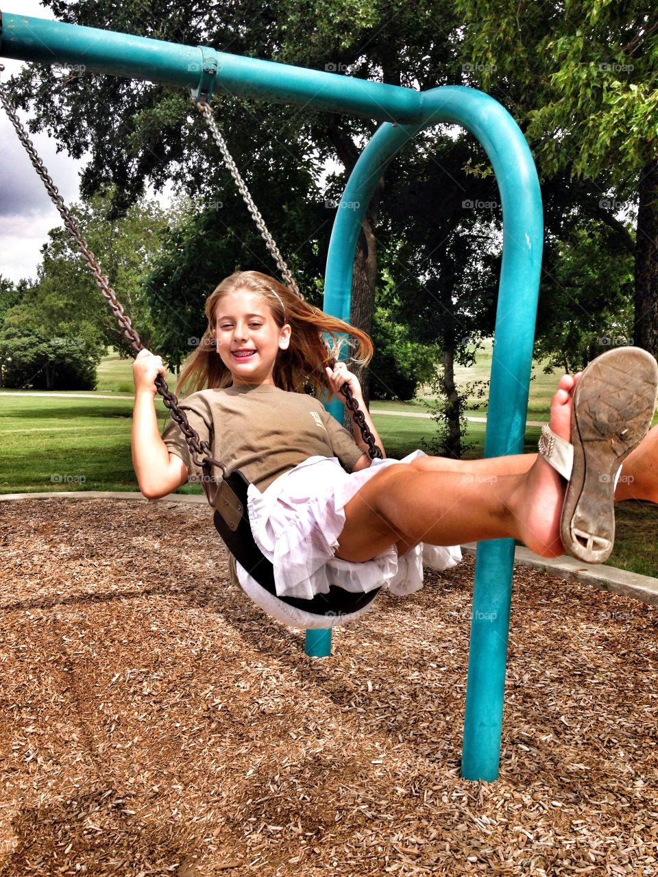 Smile and swing. Girl smiling on a swing at the park