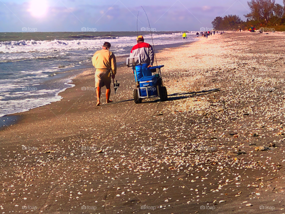 Brothers enjoying the setting sun after fishing and bonding on a shell covered beach.