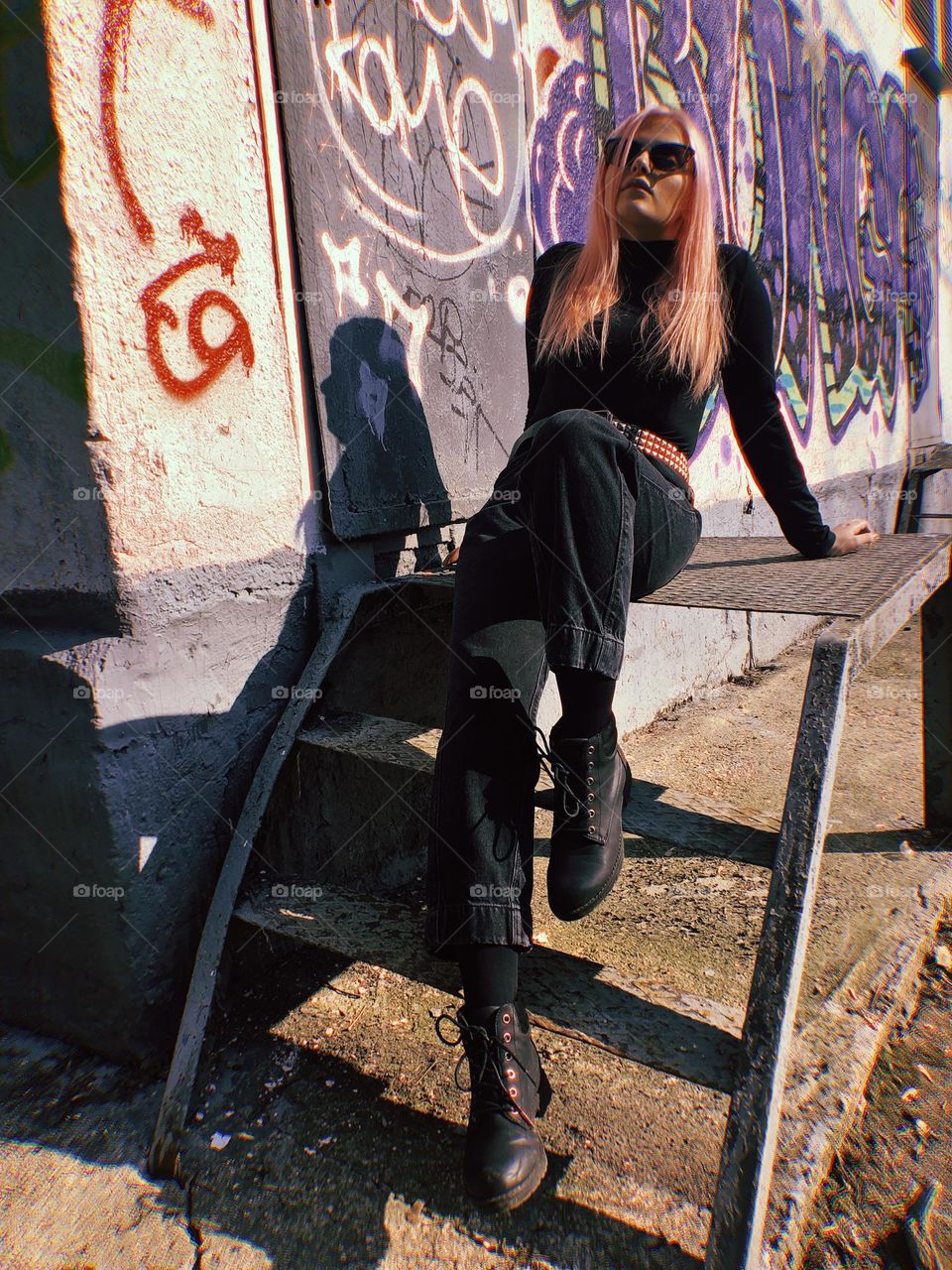 A young woman with pink hair on the background of a graffiti wall