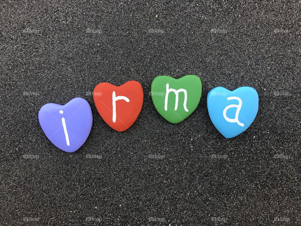 Irma, feminine name with colored heart stones over black volcanic sand