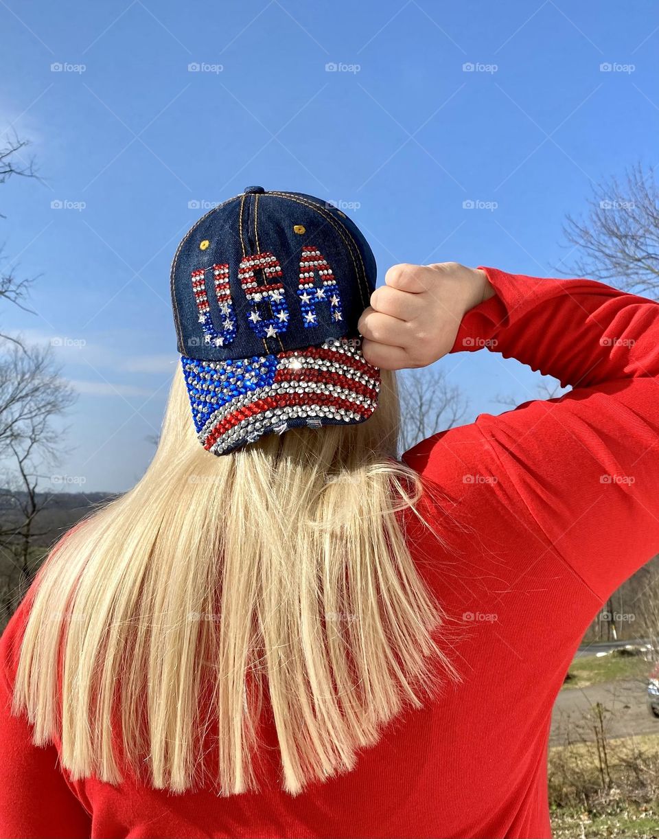 Woman with long blonde hair wearing a baseball hat 