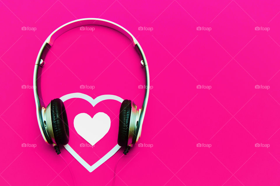 Headphones and heart on pink background with copy space 