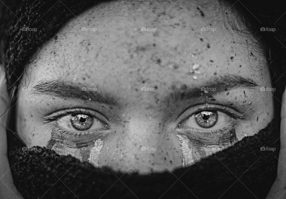 Black and white photograph of a sad girl, with tears and shocking eyes