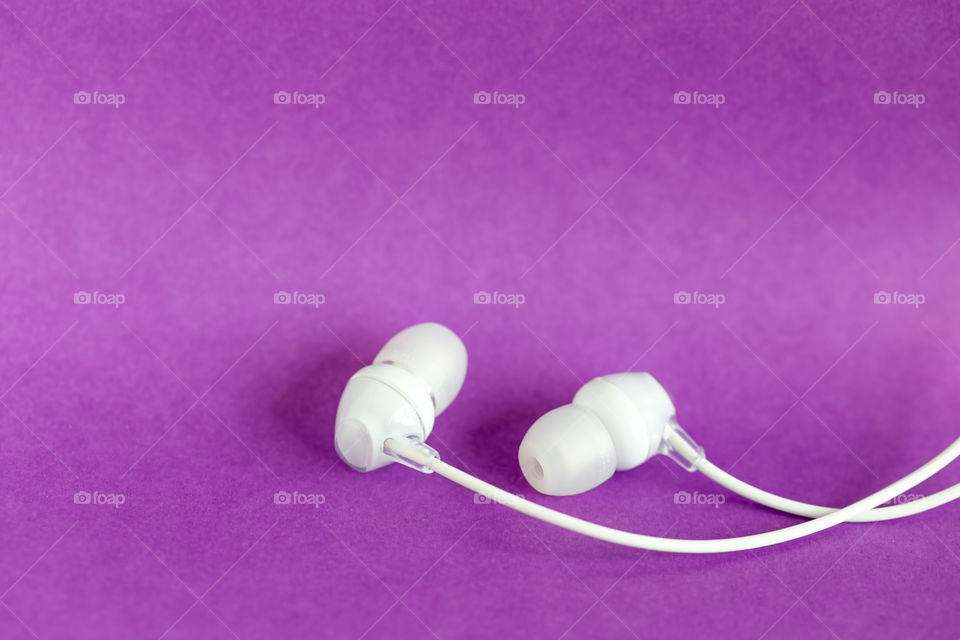Simple white headphones on purple background