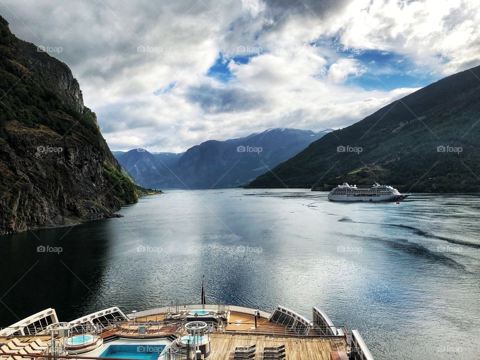 Sailing through the fjords in Norway. This was in flam on The Queen Mary 2. Cloudy blue sky reflecting on the water. 