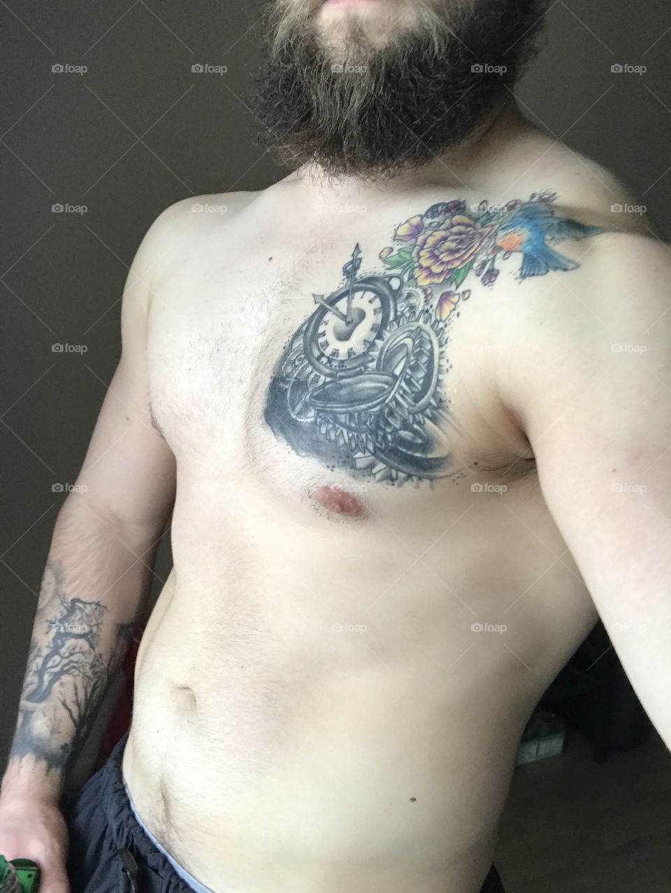 Gym body with colorful tattoos and a beard.