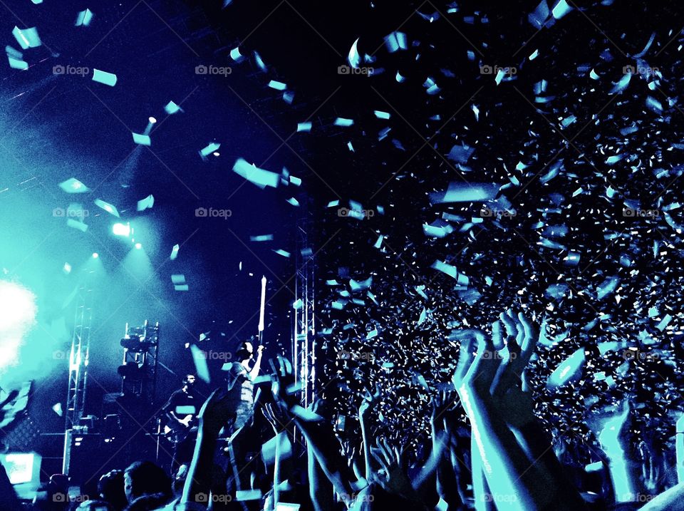 Encore. Fans cheer at a concert after confetti is fired into the air.