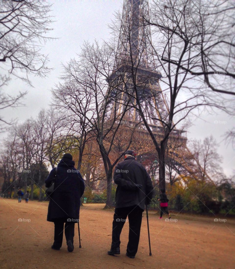 Never Too Old for Romance. An elderly couple takes their daily walk together in front of the Eiffel Tower. -City of Lovers, Paris, France