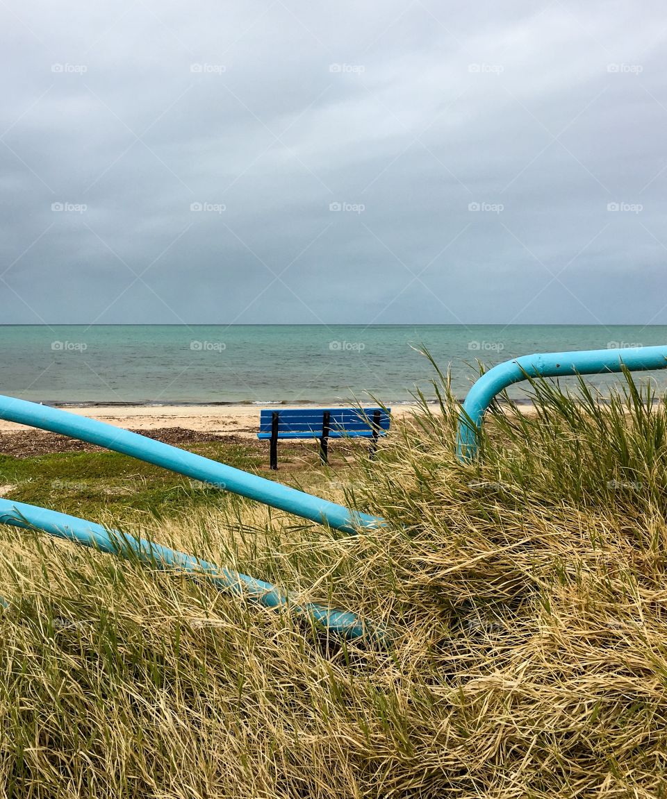 Aqua blue bench on the beach at the seashore, remote