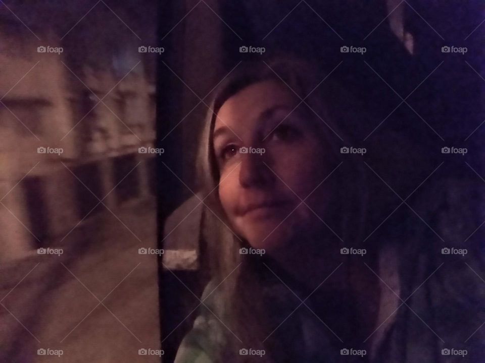 Middle aged Woman with long hair and brown eyes, gazing upwards out of a Coach / Bus Window at Night time, riding the road between Chefchouen (the Blue City) and Tangier in Morocco, Africa. The woman looks happy, thoughtful, relaxed and in a daydream