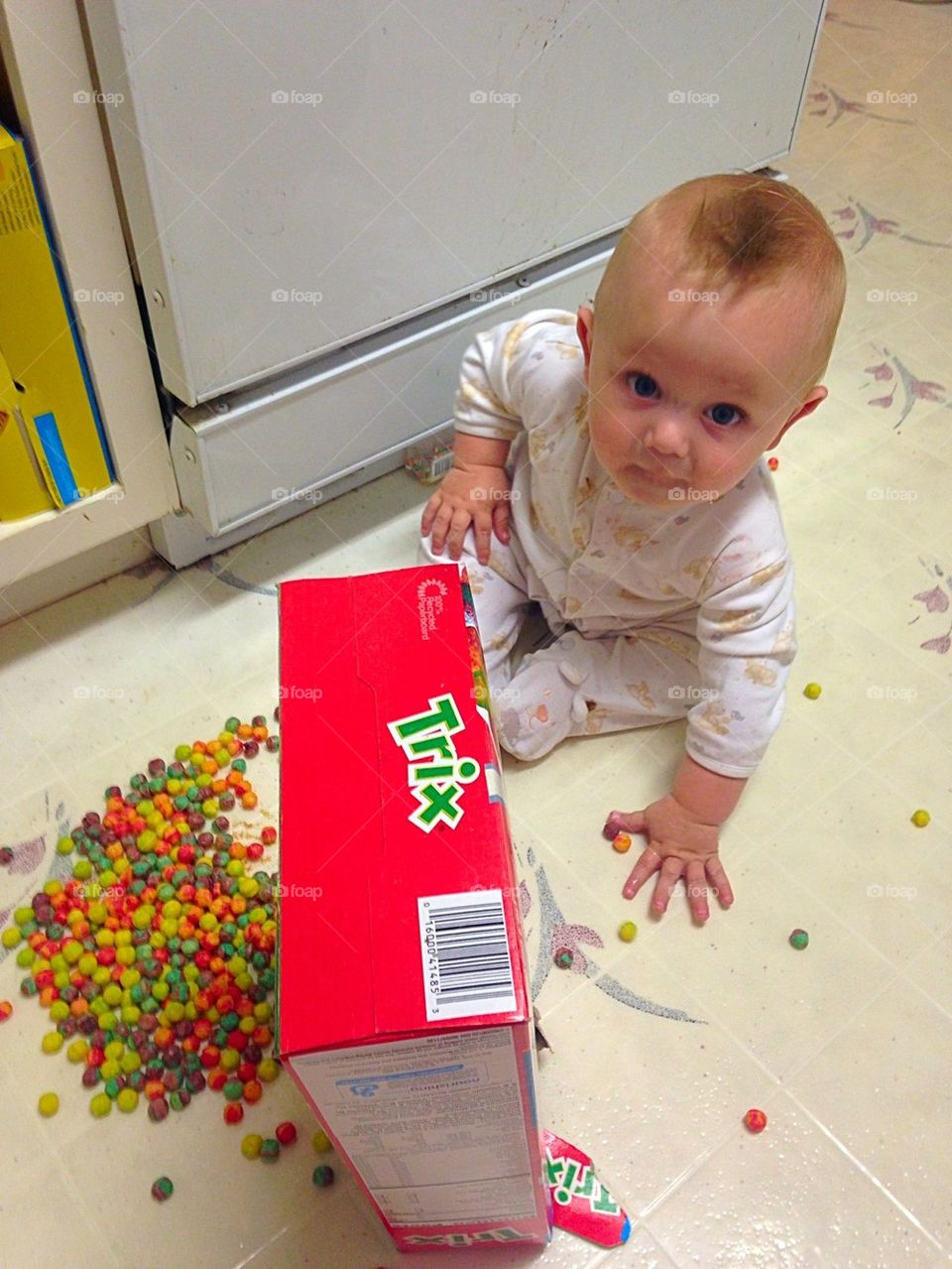 Toddler with colorful candies and box on floor