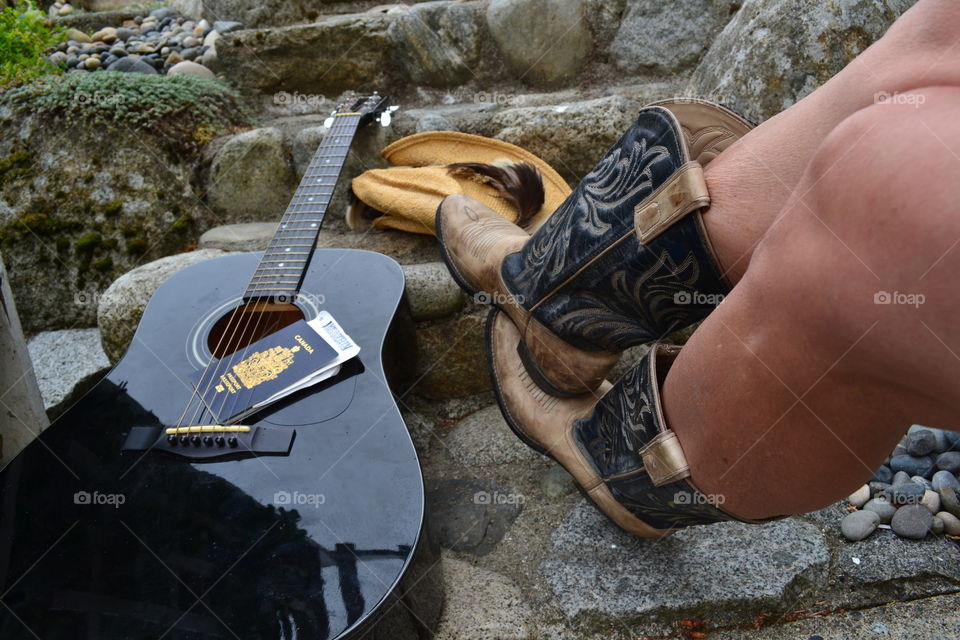 Country western musician woman in cowboy boots with guitar and hat