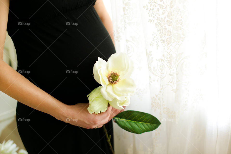Pregnant woman holding white flower