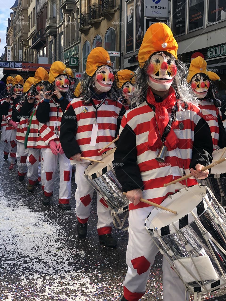 a large crowd of people running in the city among large buildings. a crowd of people in masquerade costumes and masks at a fundamental festival in Switzerland. people in bright costumes on a holiday