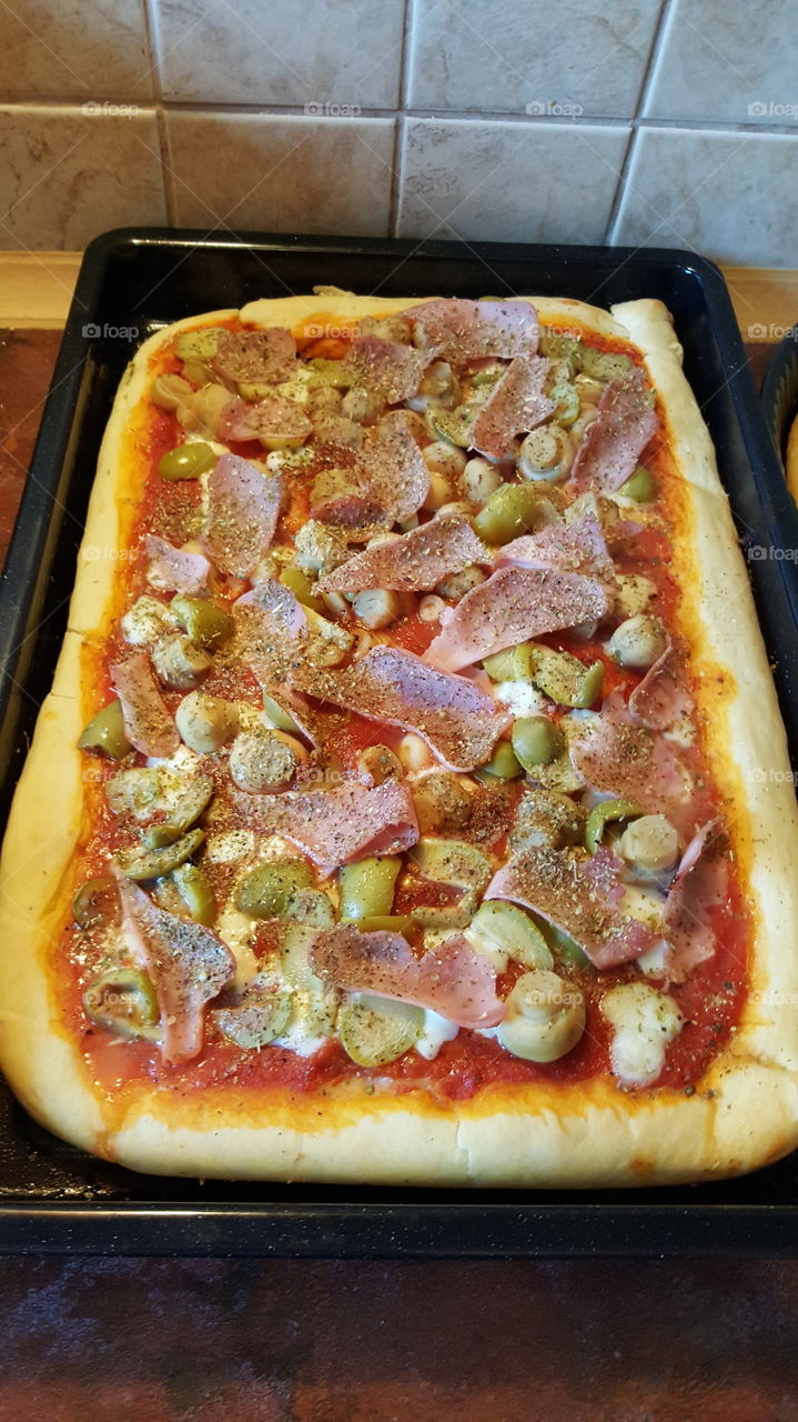 Pizza with mozzarella of Bufala, tomato sauce, Origan, green olives, mushrooms and ham