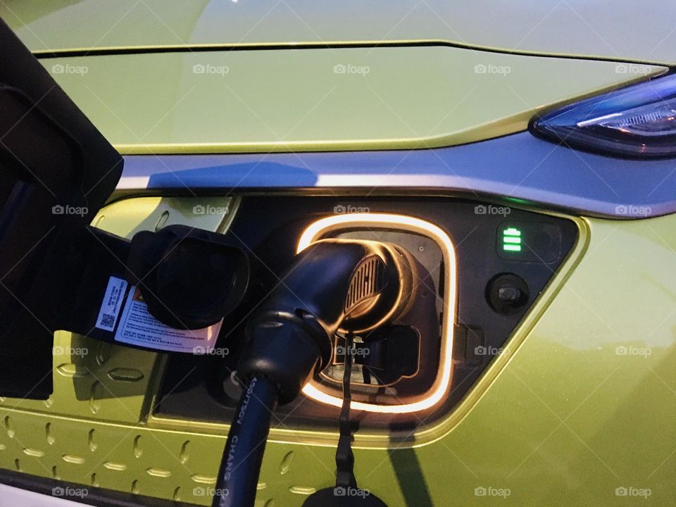 Green electric car on charger close up 