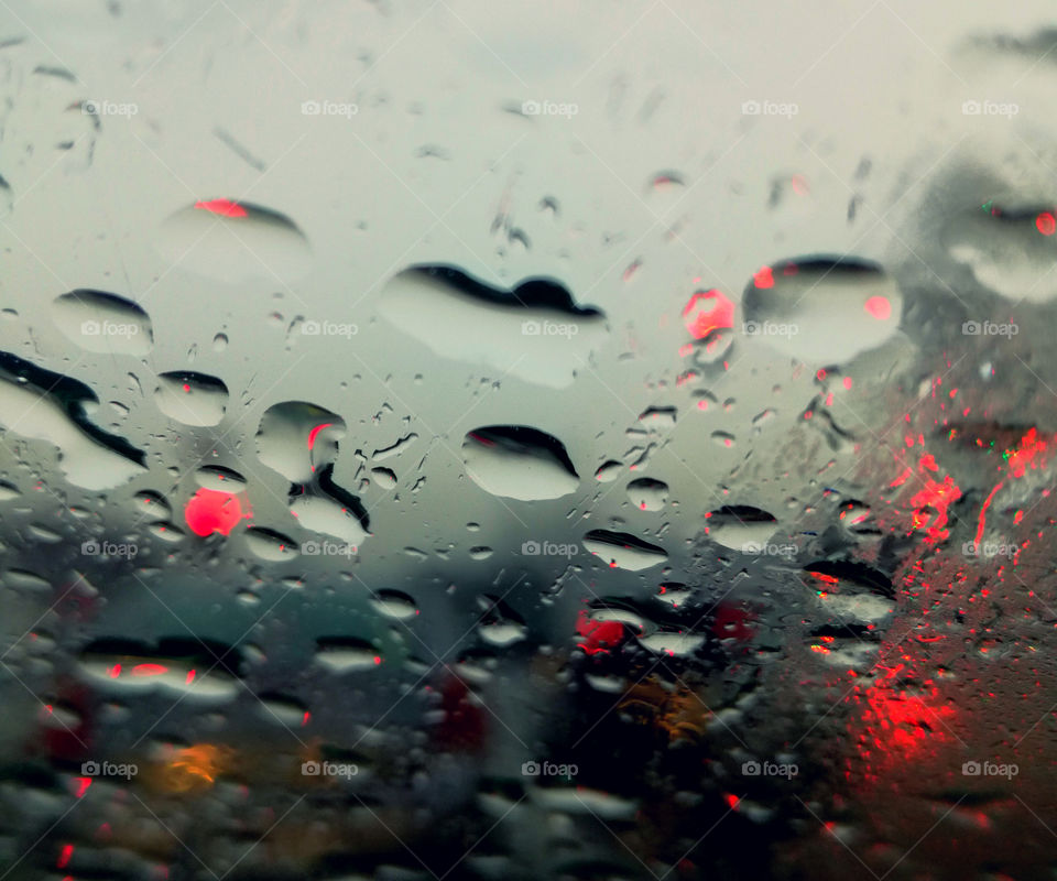 perfect rain drops on the glass of the car and colors from traffic light