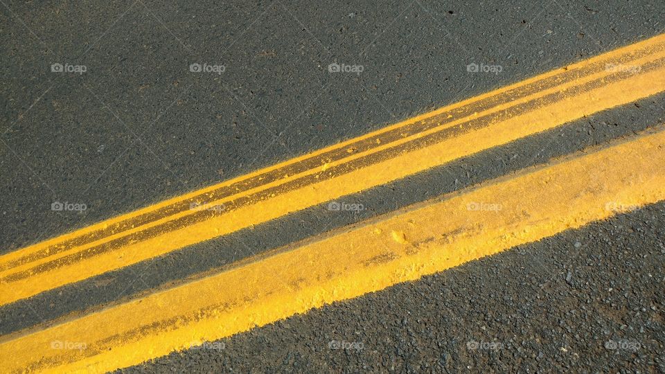 O asfalto com as faixas amarelas.