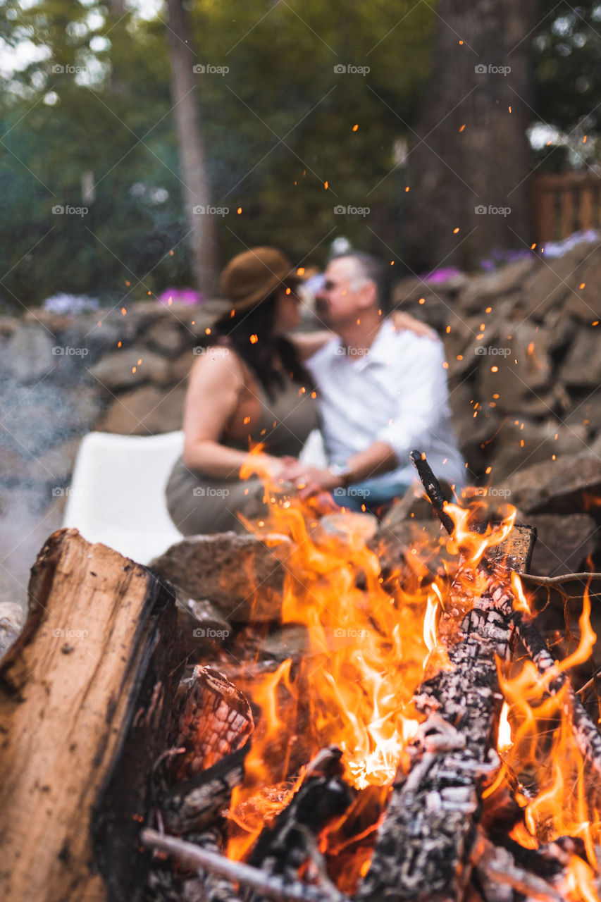 A couple cuddles near a bonfire on a summer evening 