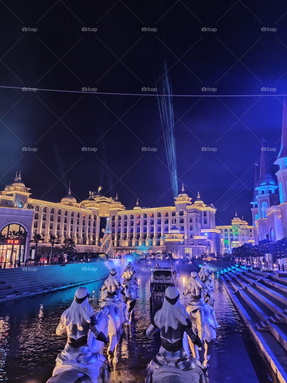 A night photo of iluminated landscape and cityscape with avenue with a hotel and water channel