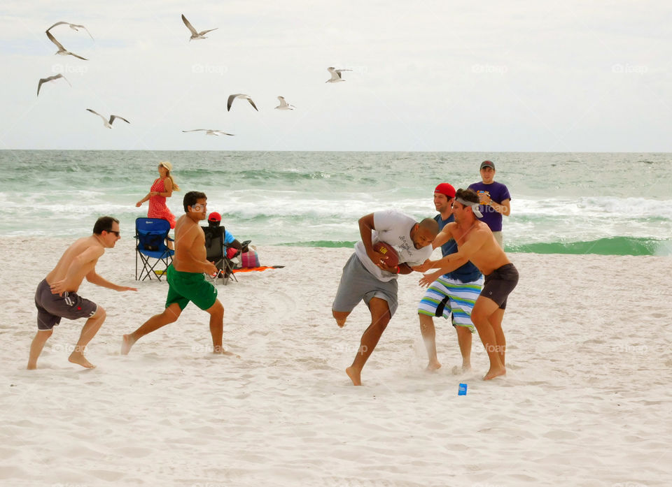 A group of visitors and local people play a game of tag beach football in front of the Gulf of Mexico!
